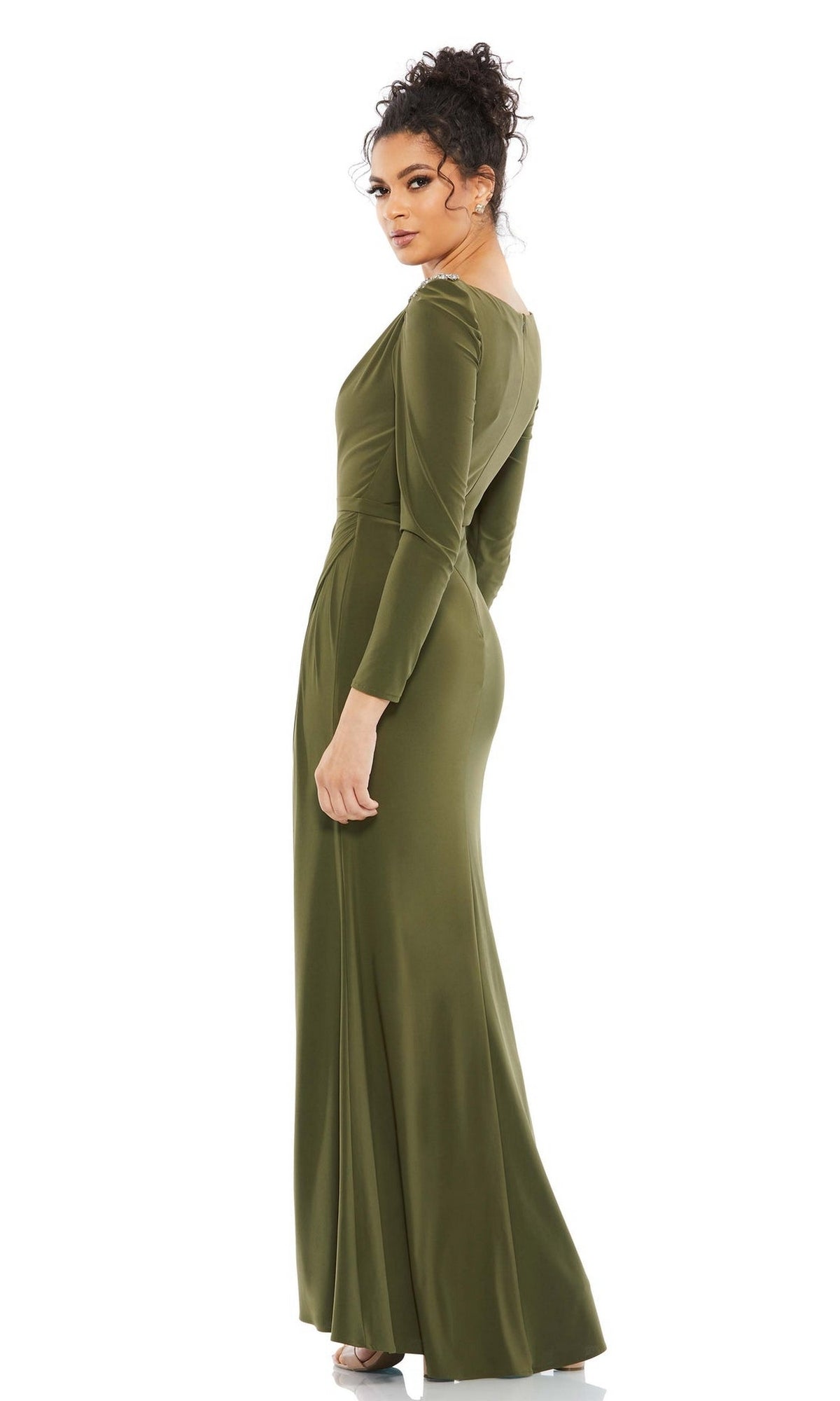 A woman in the Long Formal Dress 55695 by Mac Duggal, featuring long sleeves, a high neck, and olive green floor-length design, stands turned slightly to the side against a plain white background.